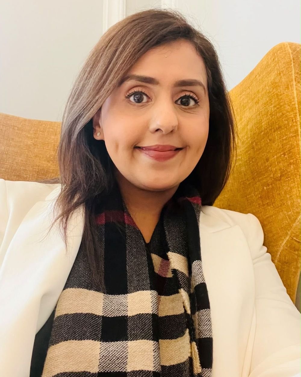 Humma, Certified Emotion Code&reg; Practitioner, smiling in a mustard armchair